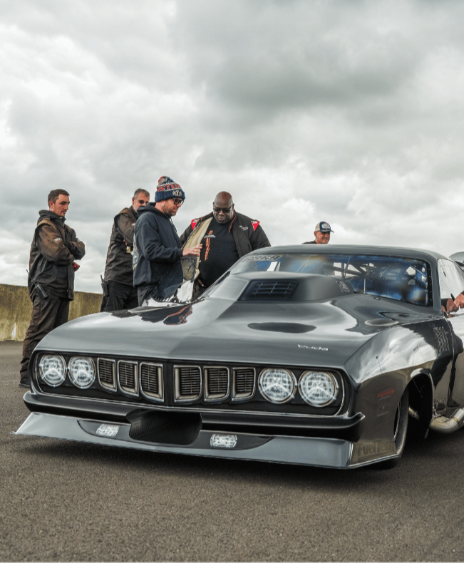 Carl Cox DJ and Group of people inspecting a classic car on a cloudy day